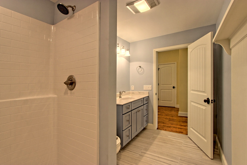 Aménagement d'une salle de bain éclectique de taille moyenne avec un placard à porte shaker, des portes de placard bleues, WC à poser, un mur bleu, un sol en carrelage de céramique, un lavabo encastré, un plan de toilette en surface solide, un sol gris, une cabine de douche avec un rideau et un plan de toilette blanc.