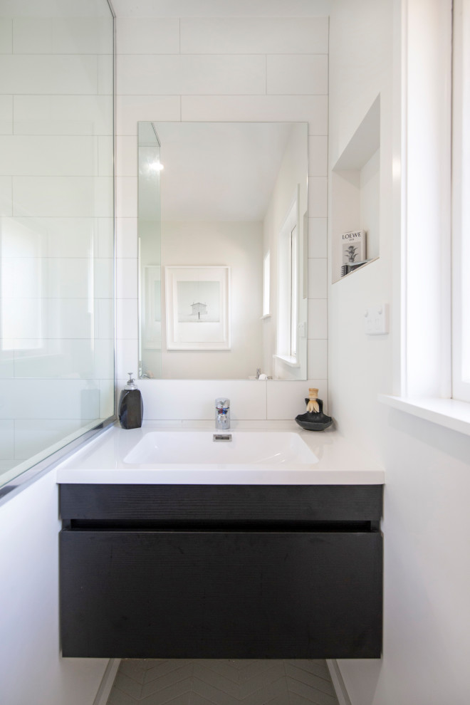 Стильный дизайн: маленькая главная ванная комната в современном стиле с плоскими фасадами, черными фасадами, угловым душем, белой плиткой, плиткой кабанчик, белыми стенами, полом из керамогранита, монолитной раковиной, столешницей из искусственного кварца, серым полом, душем с распашными дверями, белой столешницей, тумбой под одну раковину и подвесной тумбой для на участке и в саду - последний тренд