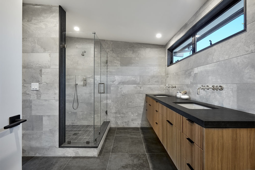 Ispirazione per una stanza da bagno moderna con ante lisce, ante in legno scuro, doccia ad angolo, piastrelle grigie, lavabo sottopiano, pavimento grigio, porta doccia a battente e top nero