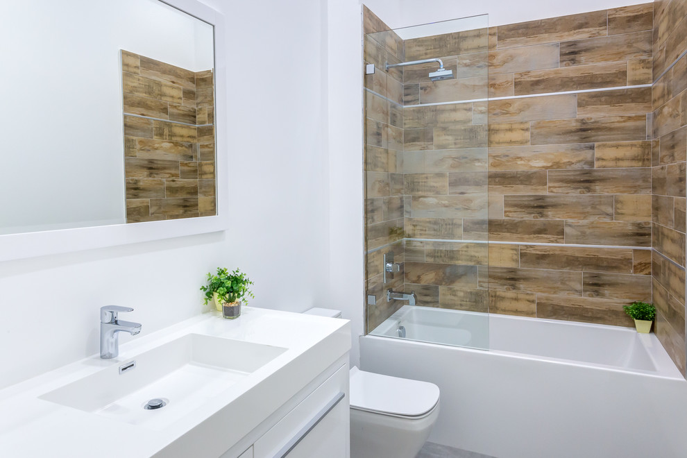 Ejemplo de cuarto de baño actual con lavabo integrado, bañera empotrada, combinación de ducha y bañera y sanitario de dos piezas