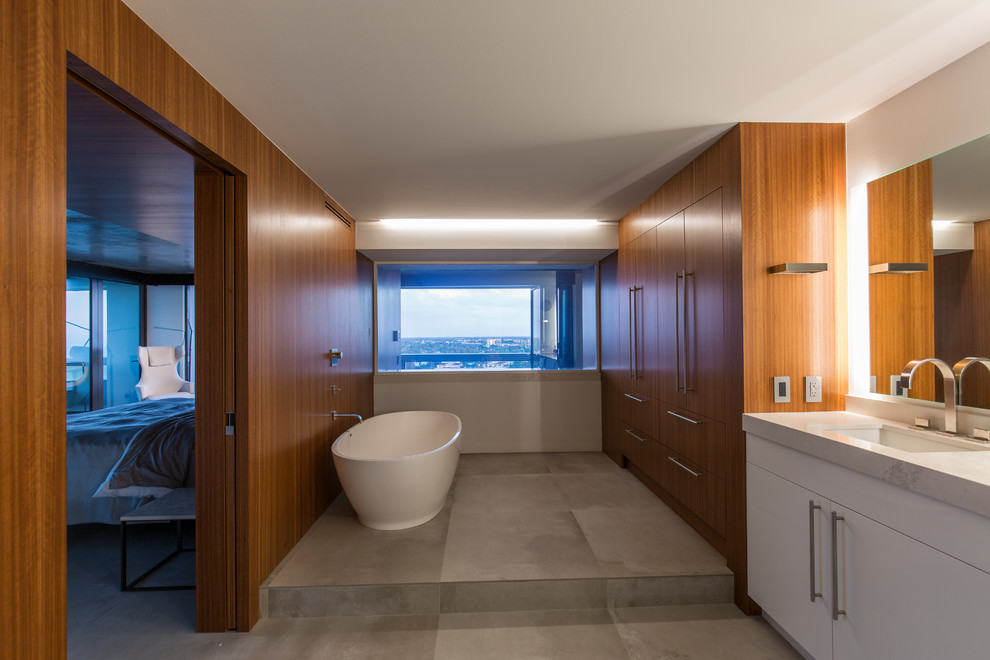Идея дизайна: ванная комната в современном стиле с светлыми деревянными фасадами, отдельно стоящей ванной, белыми стенами, мраморной столешницей, серым полом и белой столешницей
