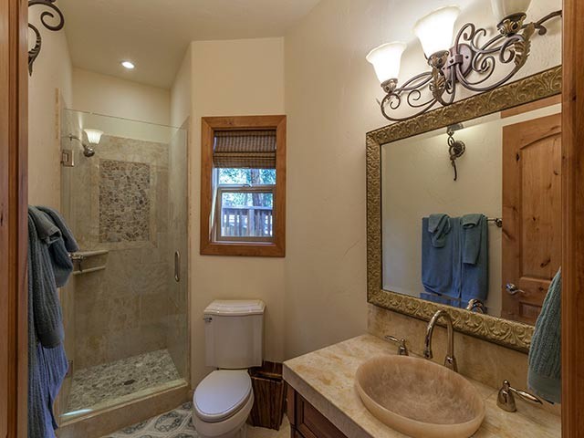 Immagine di una stanza da bagno mediterranea di medie dimensioni con lavabo da incasso, ante con bugna sagomata, ante in legno bruno, top in granito, WC monopezzo, piastrelle gialle, piastrelle in pietra, pareti beige e pavimento in travertino