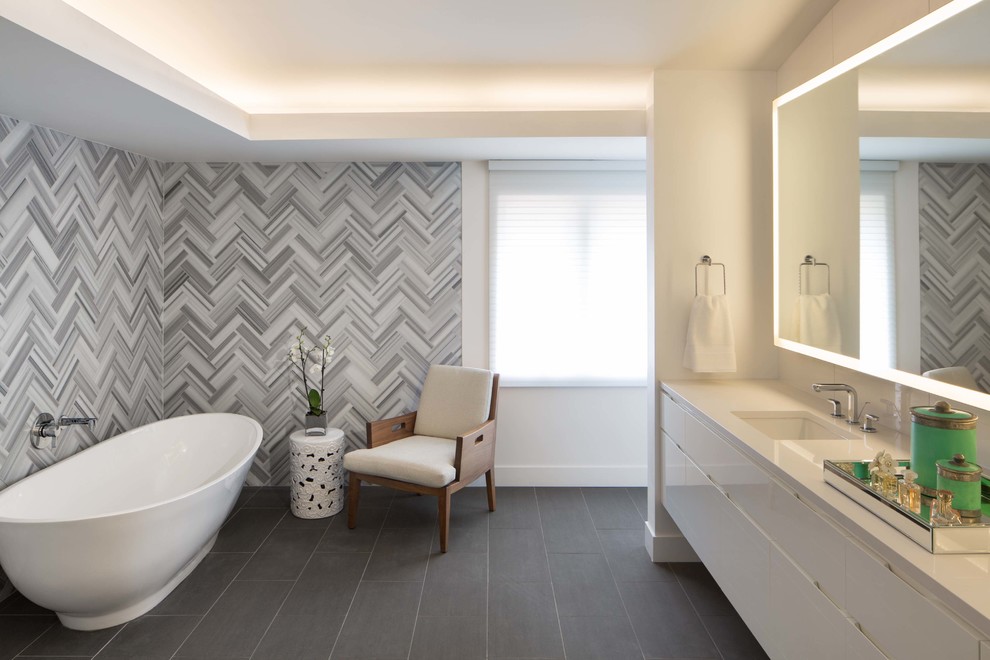 Идея дизайна: главная ванная комната в современном стиле с плоскими фасадами, белыми фасадами, отдельно стоящей ванной, серой плиткой, разноцветной плиткой, белой плиткой, белыми стенами, врезной раковиной и зеркалом с подсветкой