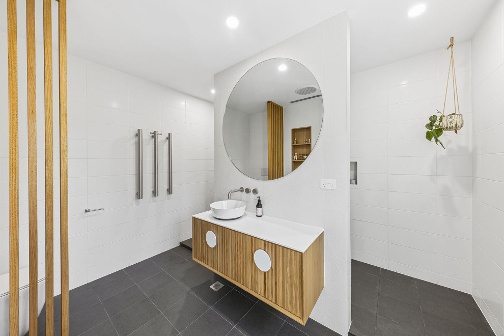 Example of a mid-sized beach style master white tile single-sink and black floor bathroom design in Sunshine Coast with white countertops, a floating vanity and white walls