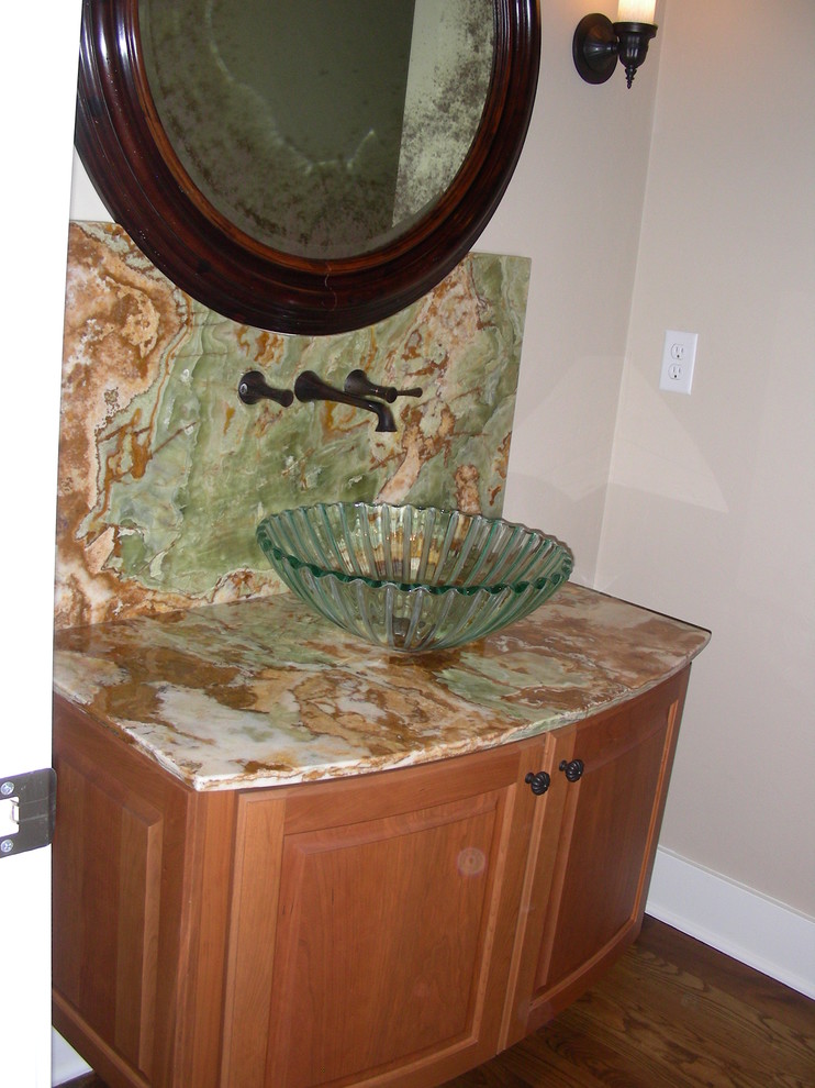 Cette image montre une petite salle d'eau traditionnelle en bois brun avec un placard à porte shaker, un mur beige, parquet foncé, une vasque et un plan de toilette en calcaire.