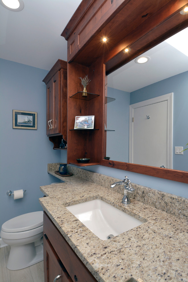 Idée de décoration pour une salle de bain principale tradition en bois brun de taille moyenne avec un placard avec porte à panneau encastré, une baignoire en alcôve, un combiné douche/baignoire, WC séparés, un carrelage beige, des carreaux de céramique, un mur bleu, un sol en carrelage de céramique, un lavabo encastré et un plan de toilette en granite.