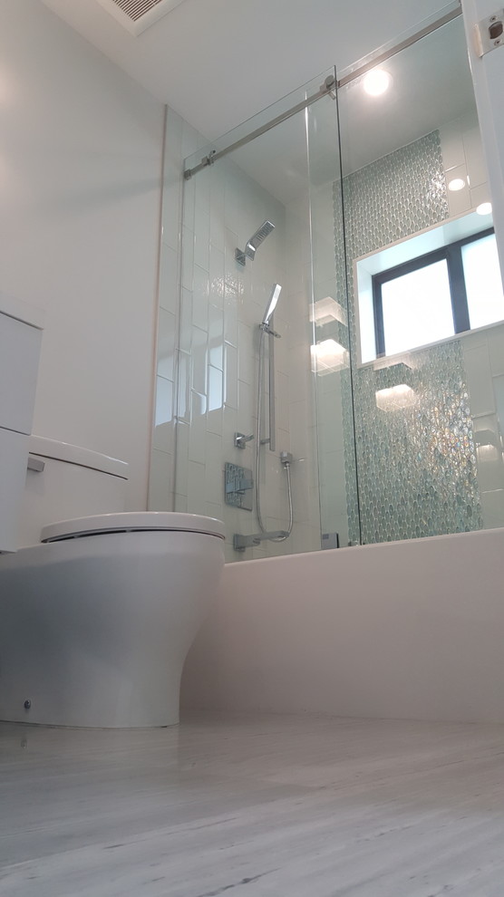 Свежая идея для дизайна: ванная комната среднего размера в стиле модернизм с плоскими фасадами, белыми фасадами, ванной в нише, душем над ванной, унитазом-моноблоком, серой плиткой, металлической плиткой, серыми стенами, мраморным полом, монолитной раковиной, столешницей из искусственного камня, серым полом и душем с раздвижными дверями - отличное фото интерьера