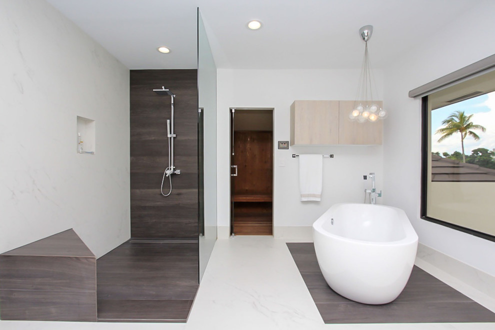 Diseño de cuarto de baño principal moderno grande con armarios con paneles lisos, puertas de armario de madera clara, bañera exenta, ducha esquinera, paredes blancas, lavabo sobreencimera y suelo blanco