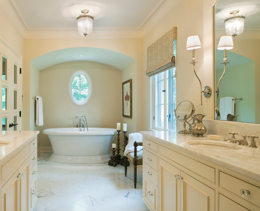 ワシントンD.C.にあるトラディショナルスタイルのおしゃれな浴室 (アンダーカウンター洗面器、落し込みパネル扉のキャビネット、ベージュのキャビネット、置き型浴槽、白いタイル) の写真