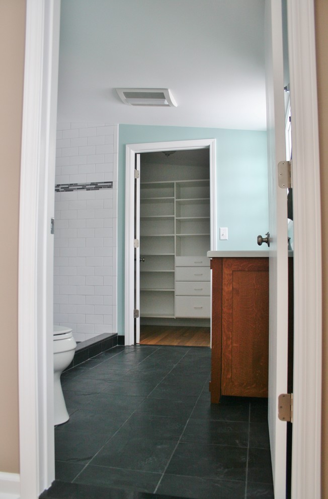 Diseño de cuarto de baño principal tradicional con ducha empotrada, sanitario de dos piezas, baldosas y/o azulejos de piedra, paredes azules y suelo de pizarra