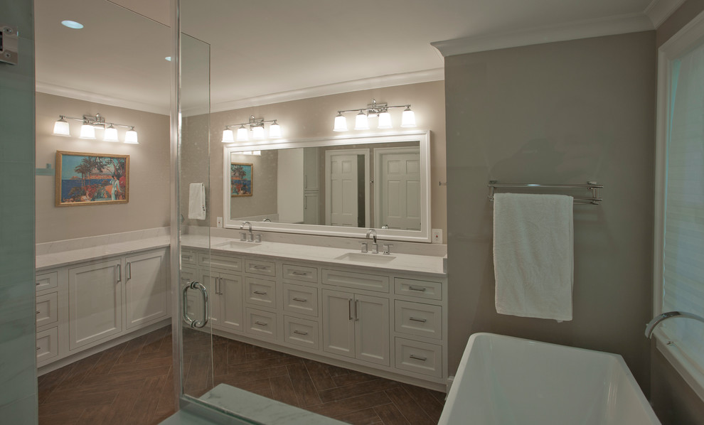 Inspiration for a large classic ensuite bathroom in DC Metro with beaded cabinets, white cabinets, a freestanding bath, a corner shower, beige walls, porcelain flooring, a submerged sink, solid surface worktops, brown floors, a hinged door and white worktops.
