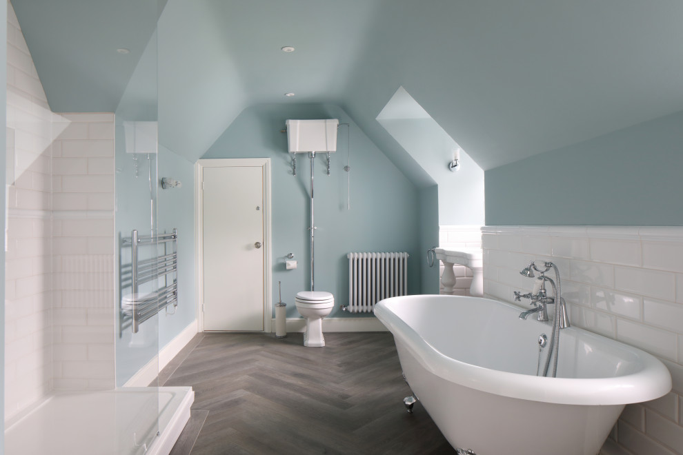 Klassisches Badezimmer mit Löwenfuß-Badewanne, weißen Fliesen, blauer Wandfarbe, dunklem Holzboden, Waschtischkonsole, braunem Boden und Einzelwaschbecken in Dorset