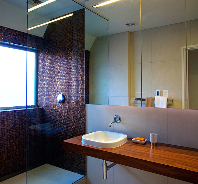 Exemple d'une salle de bain tendance avec un lavabo posé, une douche à l'italienne, un placard à porte plane, un plan de toilette en bois et un carrelage marron.