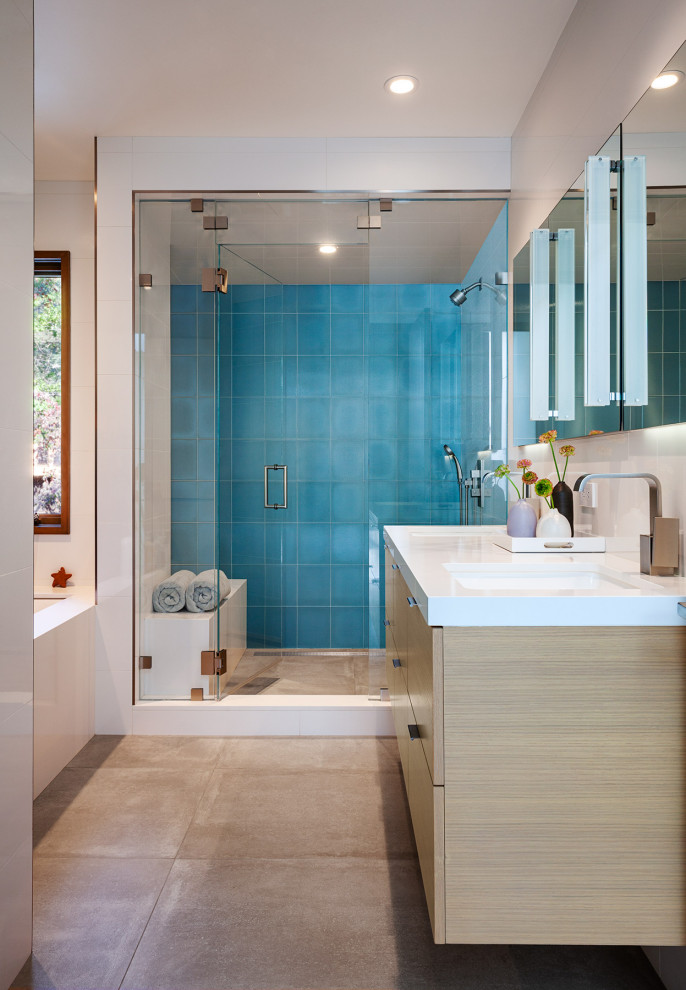 Immagine di una stanza da bagno minimal con ante lisce, ante in legno chiaro, vasca sottopiano, piastrelle blu, lavabo sottopiano, pavimento grigio, top bianco, due lavabi e mobile bagno sospeso