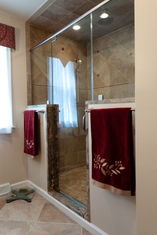 Inspiration for a mid-sized timeless 3/4 multicolored tile and porcelain tile porcelain tile double shower remodel in Philadelphia with a console sink, recessed-panel cabinets, dark wood cabinets, granite countertops, a one-piece toilet and beige walls