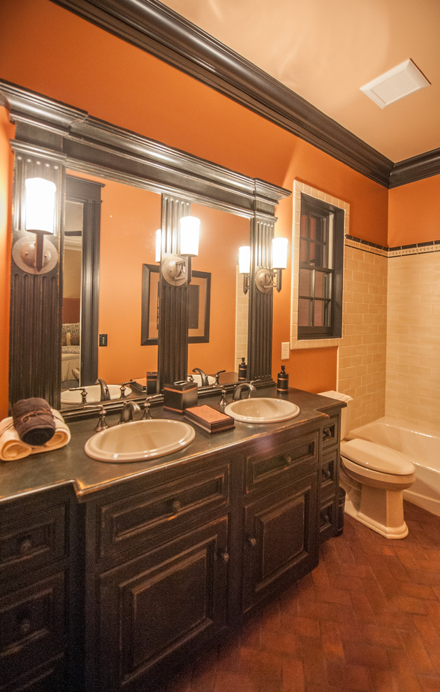 На фото: главная ванная комната среднего размера в стиле рустика с фасадами с выступающей филенкой, искусственно-состаренными фасадами, накладной ванной, душем над ванной, унитазом-моноблоком, коричневой плиткой и оранжевыми стенами с