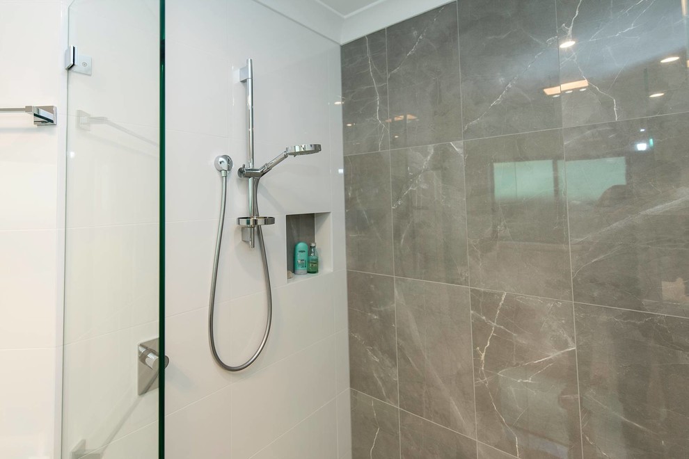 Minimalist master white tile and ceramic tile porcelain tile, beige floor and double-sink alcove shower photo in Sydney with flat-panel cabinets, dark wood cabinets, a wall-mount toilet, white walls, an integrated sink, a hinged shower door, white countertops, a niche and a floating vanity