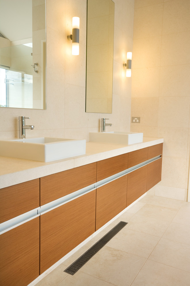 Imagen de cuarto de baño moderno de tamaño medio con lavabo encastrado, armarios con paneles lisos, puertas de armario de madera oscura, encimera de cuarzo compacto, baldosas y/o azulejos beige, baldosas y/o azulejos de piedra y paredes beige