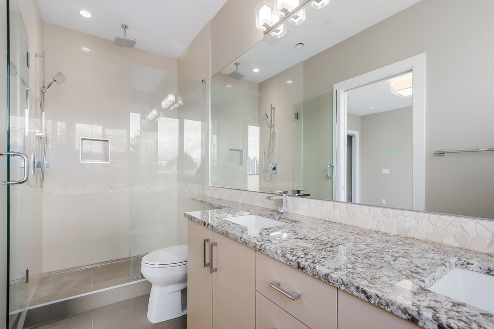 This is an example of a small modern ensuite bathroom in Vancouver with a submerged sink, flat-panel cabinets, light wood cabinets, granite worktops, an alcove shower, a two-piece toilet, grey tiles, mosaic tiles, beige walls and ceramic flooring.
