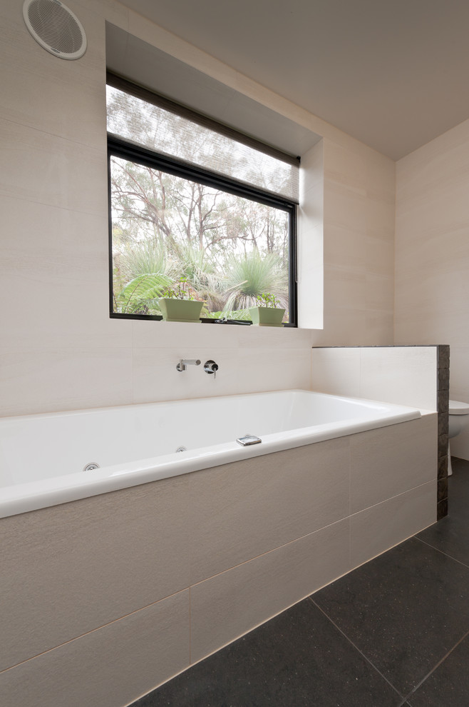 Inspiration pour une salle de bain principale design de taille moyenne avec des portes de placard noires, une baignoire posée, une douche ouverte, WC à poser et un mur beige.