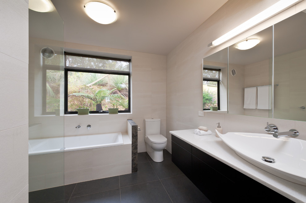 Modelo de cuarto de baño principal contemporáneo de tamaño medio con puertas de armario negras, bañera encastrada, ducha abierta, sanitario de una pieza y paredes beige