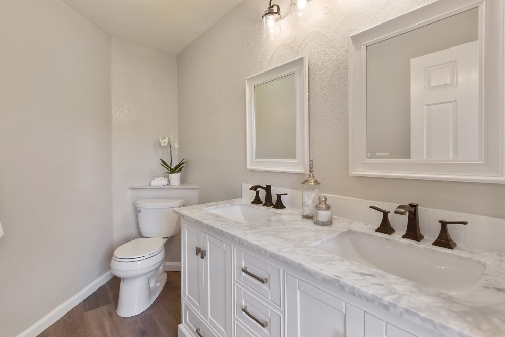 Mid-sized elegant laminate floor, brown floor and double-sink bathroom photo in San Francisco with shaker cabinets, white cabinets, gray walls, an undermount sink, marble countertops, gray countertops and a built-in vanity