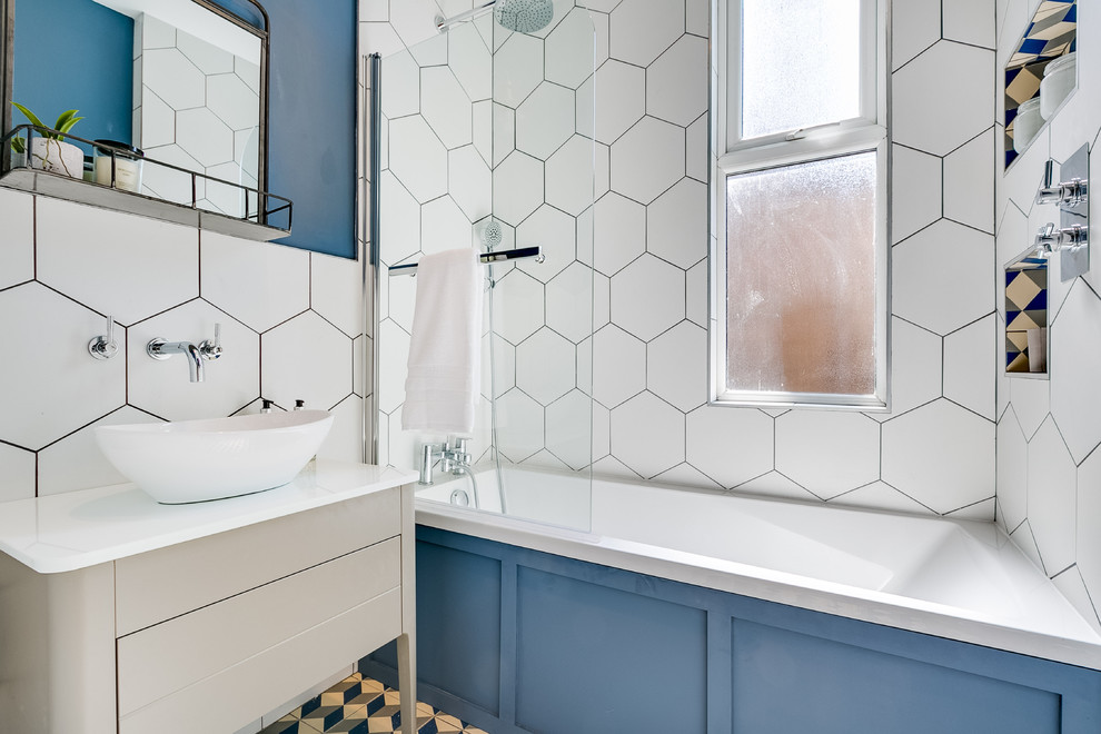 Photo of a contemporary shower room bathroom in London with flat-panel cabinets, beige cabinets, a built-in bath, a shower/bath combination, white tiles, blue walls, a vessel sink, multi-coloured floors, an open shower and white worktops.