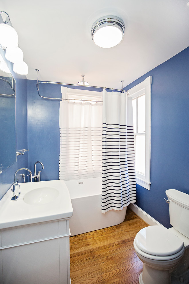 Idéer för ett litet modernt badrum för barn, med skåp i shakerstil, vita skåp, ett fristående badkar, en dusch/badkar-kombination, en toalettstol med hel cisternkåpa, blå kakel, blå väggar, ljust trägolv, ett fristående handfat, granitbänkskiva, brunt golv och dusch med duschdraperi