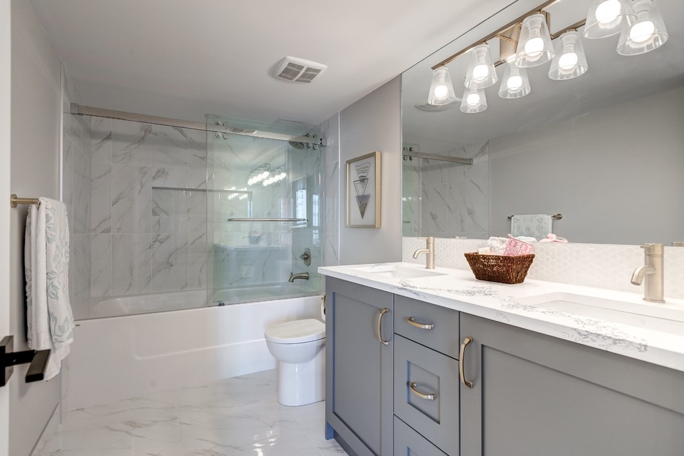 Example of a mid-sized trendy master white tile and porcelain tile porcelain tile and white floor bathroom design in Calgary with shaker cabinets, gray cabinets, a one-piece toilet, gray walls, an undermount sink, quartz countertops and white countertops