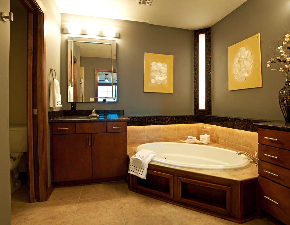 Klassisches Badezimmer mit Einbaubadewanne, Eckdusche, Wandtoilette mit Spülkasten, beigen Fliesen, schwarzen Fliesen, Keramikfliesen, grüner Wandfarbe, Keramikboden und Unterbauwaschbecken in Wichita