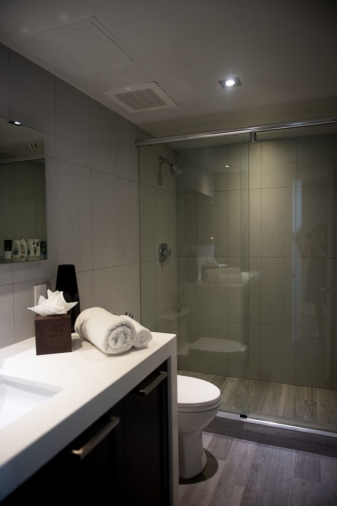 Design ideas for a medium sized classic shower room bathroom in Miami with flat-panel cabinets, dark wood cabinets, an alcove shower, a two-piece toilet, grey tiles, slate tiles, grey walls, medium hardwood flooring, a submerged sink, quartz worktops, grey floors and a sliding door.