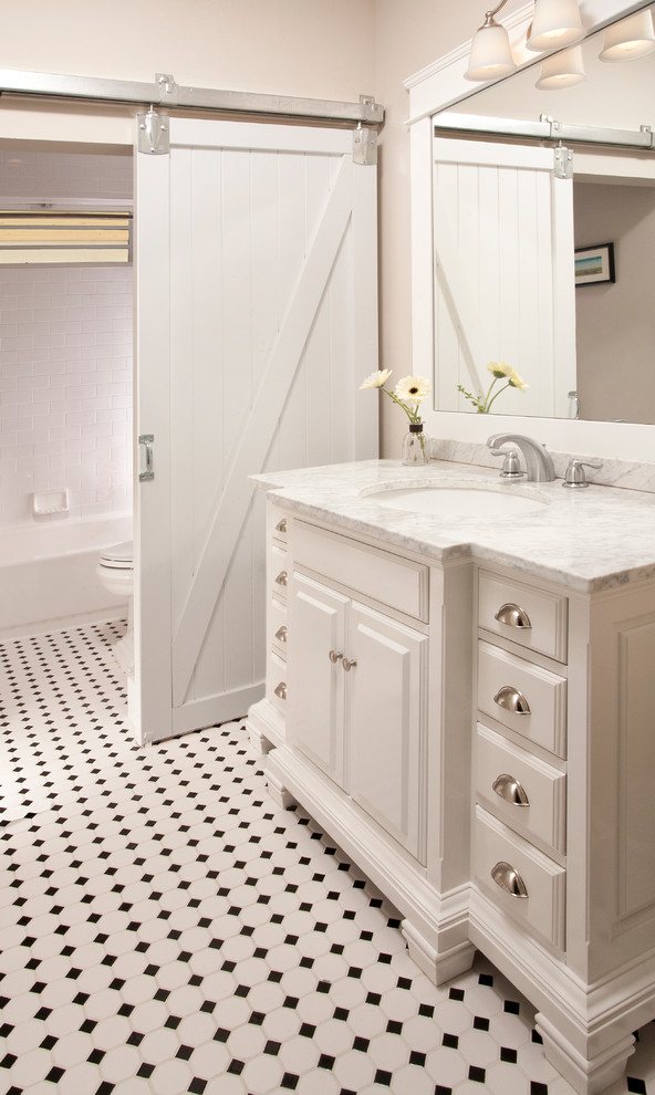 Medium sized traditional bathroom in Seattle with a submerged sink, raised-panel cabinets, white cabinets, marble worktops, an alcove bath, a shower/bath combination, a two-piece toilet, multi-coloured tiles, ceramic tiles, beige walls and ceramic flooring.