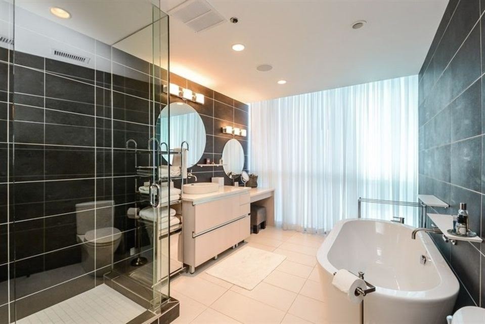 Photo of a large modern ensuite bathroom in Chicago with white cabinets, a freestanding bath, a corner shower, a one-piece toilet, black tiles, black walls, a vessel sink, flat-panel cabinets, ceramic flooring, granite worktops, ceramic tiles, beige floors and a hinged door.