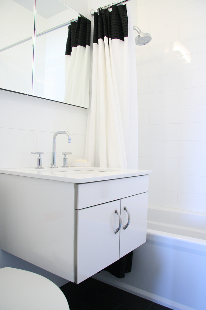 Foto på ett litet funkis badrum med dusch, med släta luckor, vita skåp, ett badkar i en alkov, en dusch/badkar-kombination, en toalettstol med separat cisternkåpa, vit kakel, porslinskakel, vita väggar, linoleumgolv, ett väggmonterat handfat och bänkskiva i akrylsten