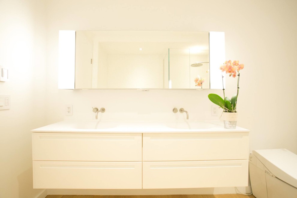 Стильный дизайн: большая главная ванная комната в современном стиле с белыми фасадами, угловой ванной, угловым душем, унитазом-моноблоком, белой плиткой, мраморной плиткой, белыми стенами, светлым паркетным полом, подвесной раковиной и душем с распашными дверями - последний тренд