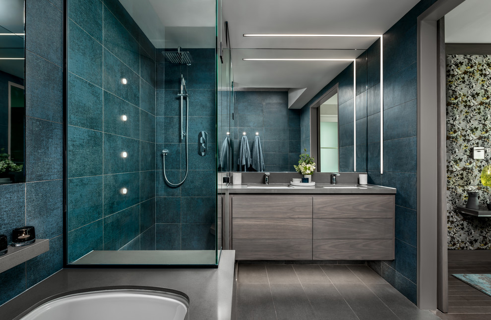 Пример оригинального дизайна: главная ванная комната среднего размера в современном стиле с плоскими фасадами, серыми фасадами, полновстраиваемой ванной, угловым душем, синей плиткой, керамогранитной плиткой, серыми стенами, полом из керамогранита, врезной раковиной, столешницей из искусственного кварца, серым полом, душем с распашными дверями и серой столешницей