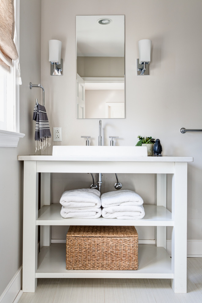 Modern inredning av ett badrum, med ett fristående handfat, öppna hyllor, vita skåp, bänkskiva i kvartsit, ett badkar i en alkov, en dusch i en alkov, grå kakel, porslinskakel, grå väggar och klinkergolv i porslin