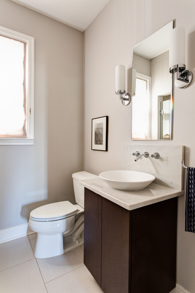 Cette image montre une salle de bain design en bois foncé avec une vasque, un placard à porte plane, un plan de toilette en quartz, des carreaux de porcelaine, un mur gris et un sol en carrelage de porcelaine.