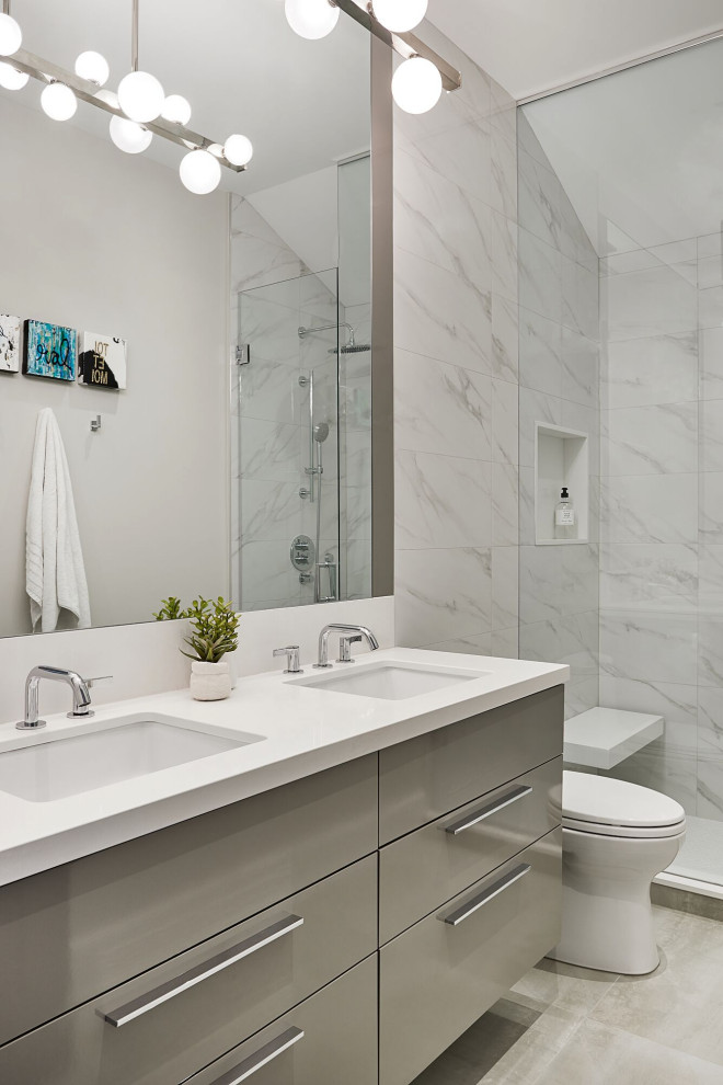 Foto de cuarto de baño actual con armarios con paneles lisos, puertas de armario grises, ducha empotrada, baldosas y/o azulejos blancos, lavabo bajoencimera, suelo gris y encimeras blancas