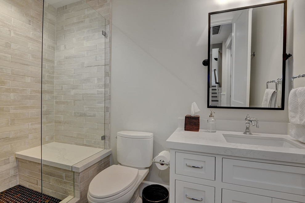 Diseño de cuarto de baño de estilo americano pequeño con puertas de armario blancas, sanitario de una pieza, baldosas y/o azulejos de piedra, paredes grises, aseo y ducha, lavabo encastrado y ducha con puerta con bisagras