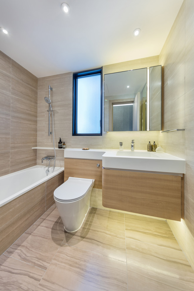 Ispirazione per una stanza da bagno con doccia design con ante lisce, ante in legno chiaro, vasca da incasso, WC sospeso, piastrelle beige, pareti beige, lavabo integrato e doccia aperta