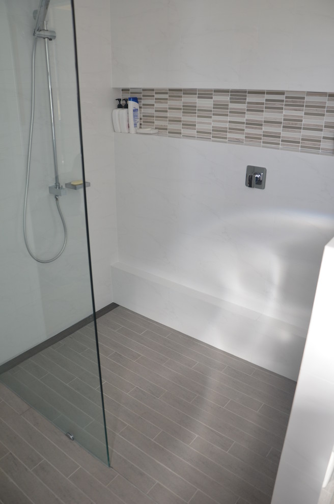 Ejemplo de cuarto de baño contemporáneo con lavabo integrado, ducha abierta, sanitario de una pieza, armarios con paneles lisos, puertas de armario blancas, encimera de acrílico, baldosas y/o azulejos blancos y baldosas y/o azulejos de porcelana