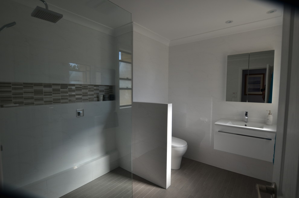 シドニーにあるお手頃価格のコンテンポラリースタイルのおしゃれな浴室 (一体型シンク、オープン型シャワー、一体型トイレ	、フラットパネル扉のキャビネット、白いキャビネット、人工大理石カウンター、白いタイル、磁器タイル) の写真