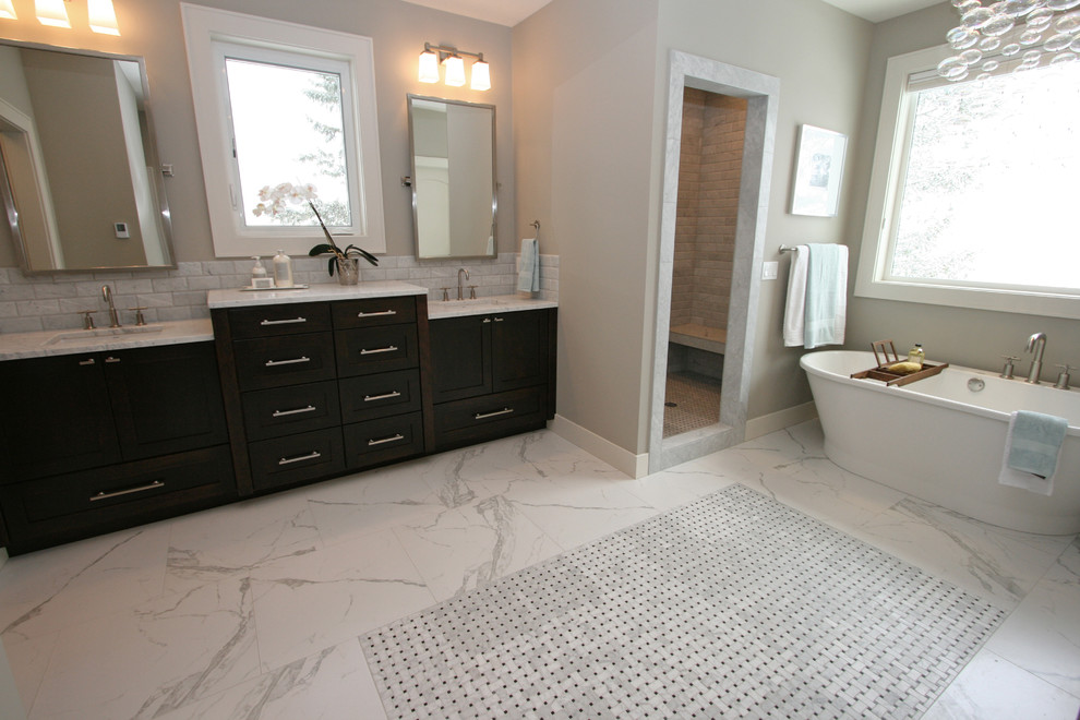 Photo of a large classic ensuite bathroom in Seattle with shaker cabinets, dark wood cabinets, a freestanding bath, an alcove shower, a two-piece toilet, white tiles, porcelain tiles, grey walls, porcelain flooring, a submerged sink and marble worktops.