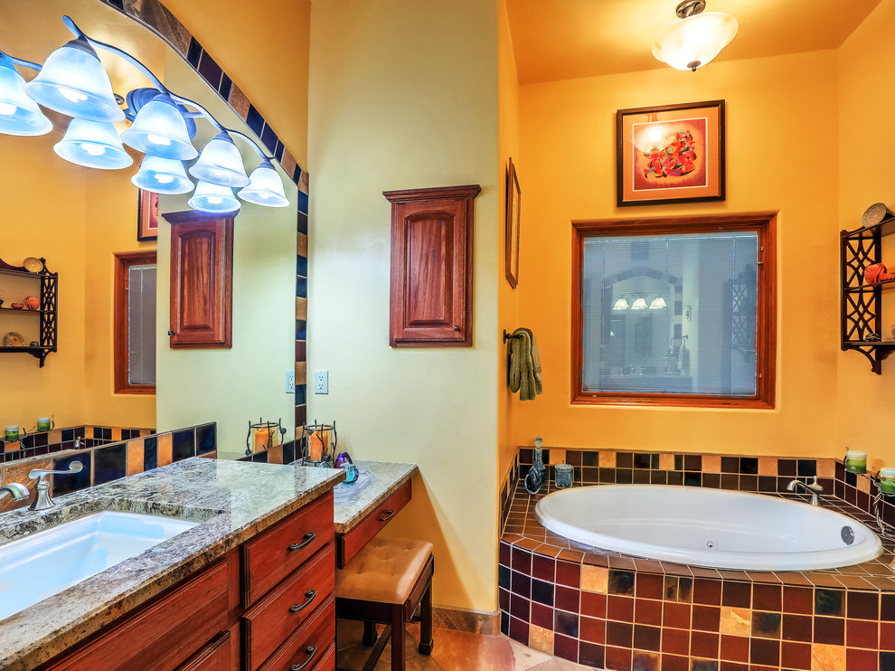 Aménagement d'une salle de bain principale sud-ouest américain en bois brun de taille moyenne avec un plan de toilette en granite, un plan de toilette marron, un placard à porte plane, une baignoire d'angle, un carrelage multicolore, des carreaux de céramique, un mur jaune, un sol en ardoise, un lavabo encastré et un sol multicolore.