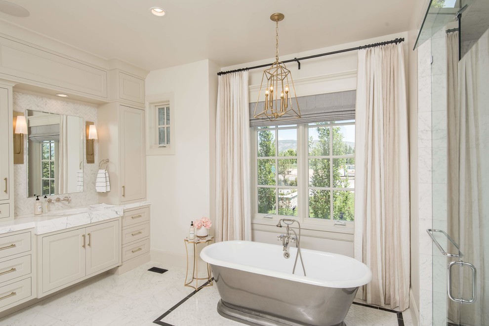 Свежая идея для дизайна: главная ванная комната в стиле неоклассика (современная классика) с фасадами с утопленной филенкой, бежевыми фасадами, отдельно стоящей ванной, белыми стенами, белым полом и белой столешницей - отличное фото интерьера