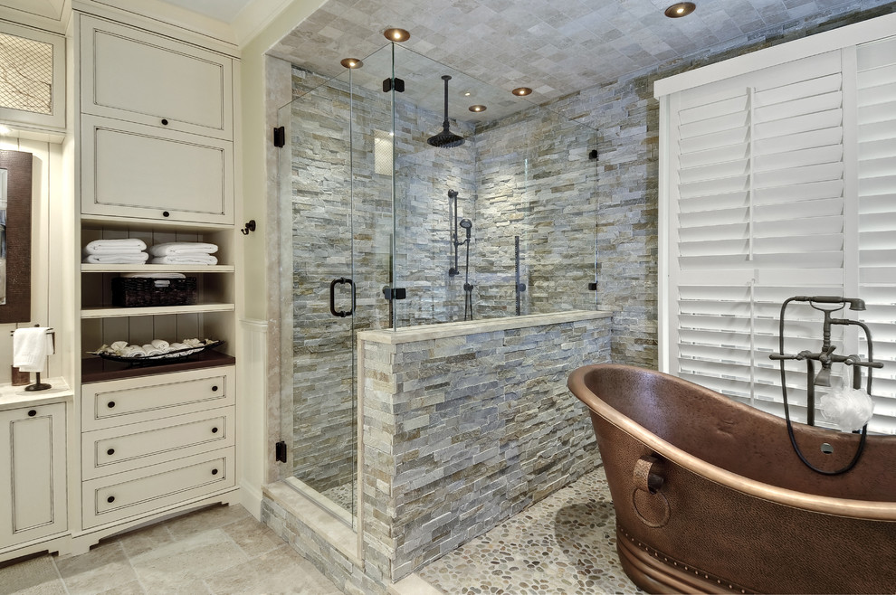 Idée de décoration pour une grande salle de bain principale tradition avec une baignoire indépendante, un carrelage de pierre, un sol en galet, un placard à porte affleurante, des portes de placard beiges, une douche d'angle, un carrelage gris, un mur beige, un plan de toilette en quartz modifié, un sol gris et un plan de toilette blanc.