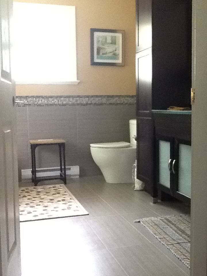 Cette image montre une grande salle de bain principale minimaliste avec un placard avec porte à panneau encastré, des portes de placard marrons, un plan de toilette en verre, une baignoire indépendante, une douche ouverte, WC à poser, un carrelage gris, mosaïque, un mur gris et un sol en carrelage de céramique.