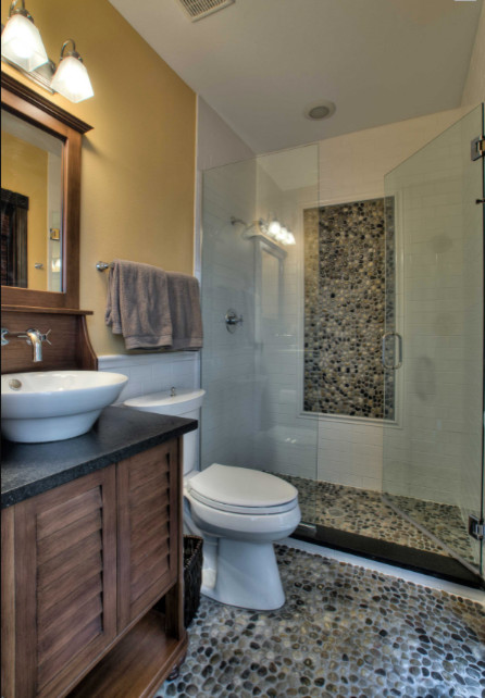 Inredning av ett klassiskt mellanstort svart svart badrum med dusch, med möbel-liknande, skåp i mellenmörkt trä, en dusch i en alkov, en toalettstol med hel cisternkåpa, gula väggar, klinkergolv i småsten, ett fristående handfat, granitbänkskiva, flerfärgat golv, dusch med gångjärnsdörr, flerfärgad kakel och mosaik