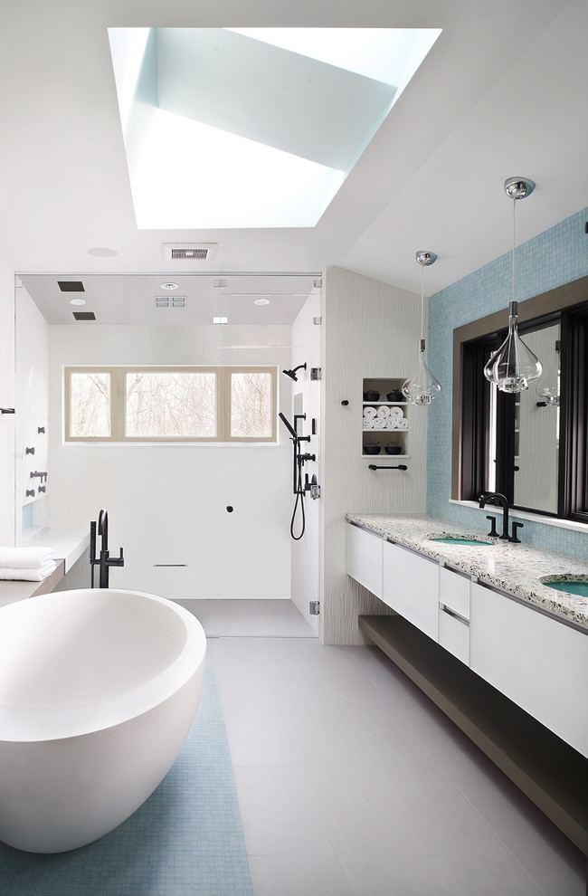 Inspiration for a large contemporary ensuite bathroom in Other with white cabinets, a freestanding bath, a built-in shower, white tiles, ceramic tiles, porcelain flooring, a submerged sink, recycled glass worktops, grey floors, a hinged door, flat-panel cabinets, white walls and grey worktops.